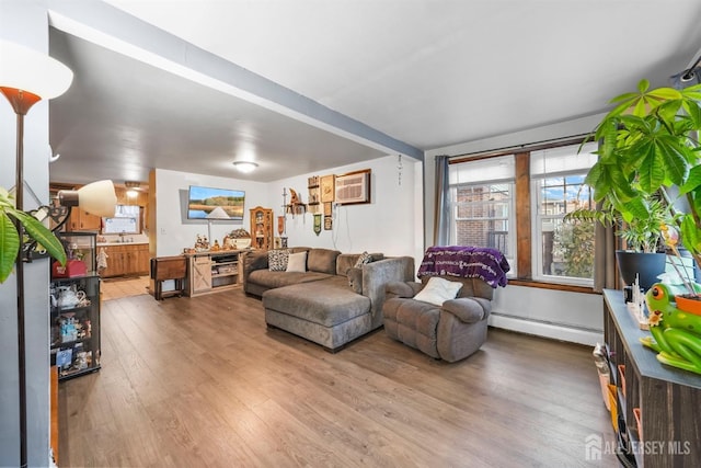 living area with a baseboard radiator, a wall mounted air conditioner, and wood finished floors