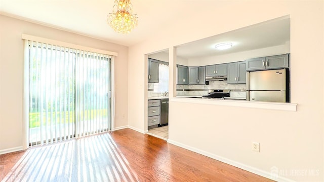 1204 Maplecrest Rd, Edison, NJ 08820 - kitchen with stainless steel appliances, under cabinet range hood, gray cabinetry, decorative backsplash, and wood finished floors