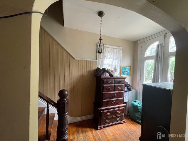 bedroom with wood walls, arched walkways, and wood finished floors