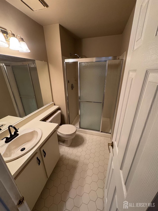 bathroom featuring vanity, toilet, tile patterned flooring, and a shower with door