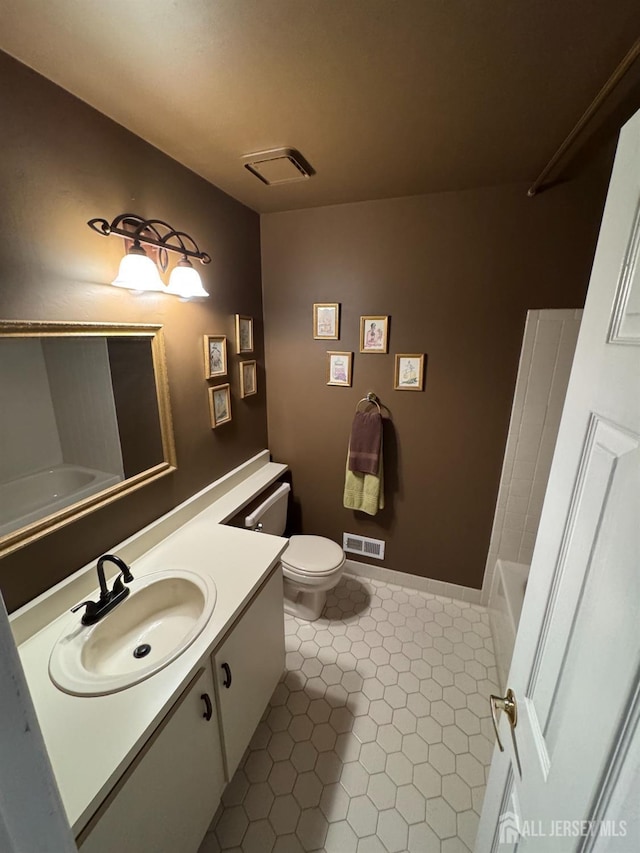 bathroom featuring vanity, tile patterned flooring, a bathtub, and toilet