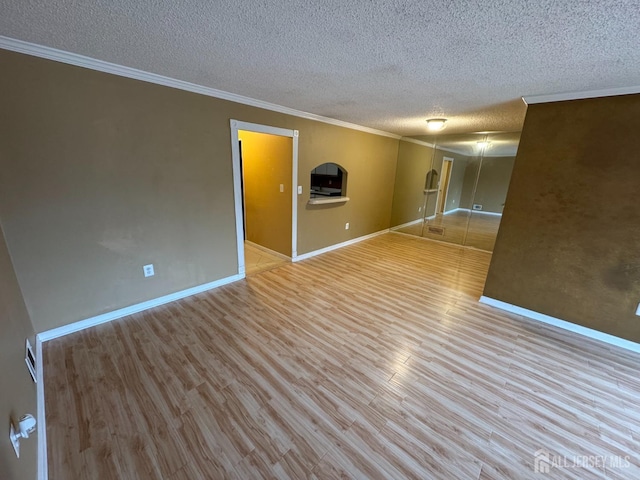 spare room featuring ornamental molding, a textured ceiling, and light wood-type flooring