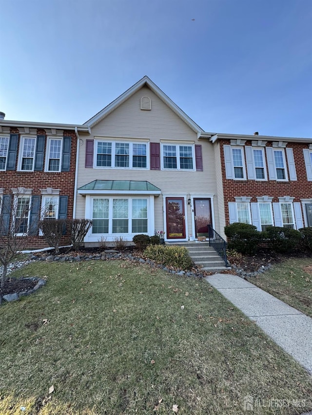 townhome / multi-family property with brick siding and a front lawn