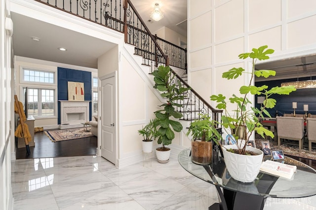 foyer with baseboards, a fireplace, stairs, a towering ceiling, and marble finish floor