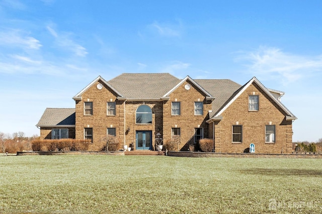 view of front of home featuring a front yard, french doors, brick siding, and roof with shingles