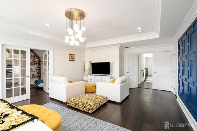 living room with a notable chandelier, ornamental molding, a tray ceiling, dark wood finished floors, and french doors