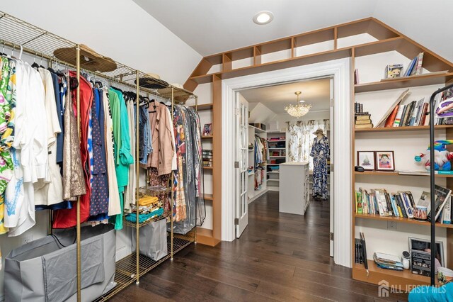 walk in closet with a notable chandelier, lofted ceiling, and wood finished floors