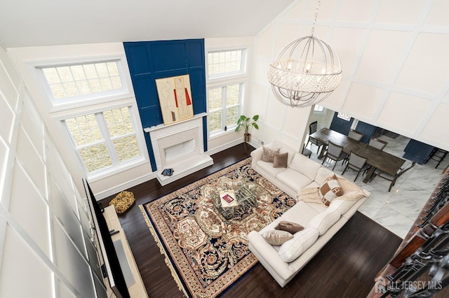 living room featuring baseboards, a notable chandelier, wood finished floors, and a decorative wall