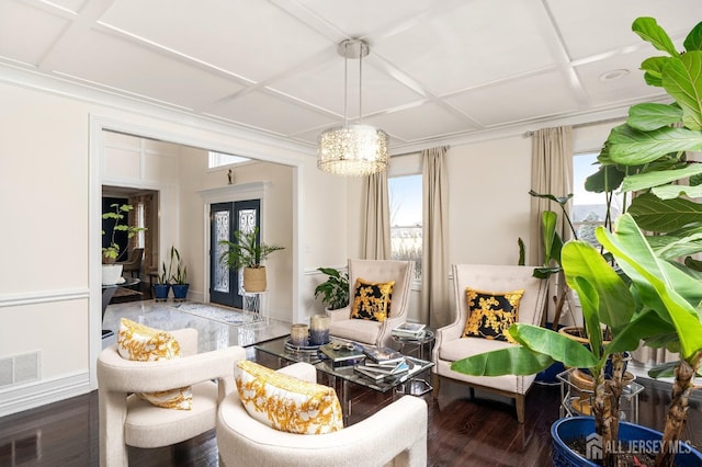 sitting room with visible vents, coffered ceiling, wood finished floors, and a notable chandelier