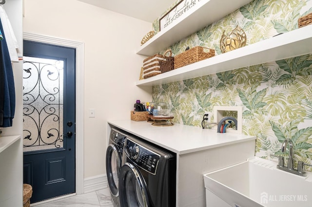 washroom featuring marble finish floor, washer and clothes dryer, a sink, wallpapered walls, and laundry area