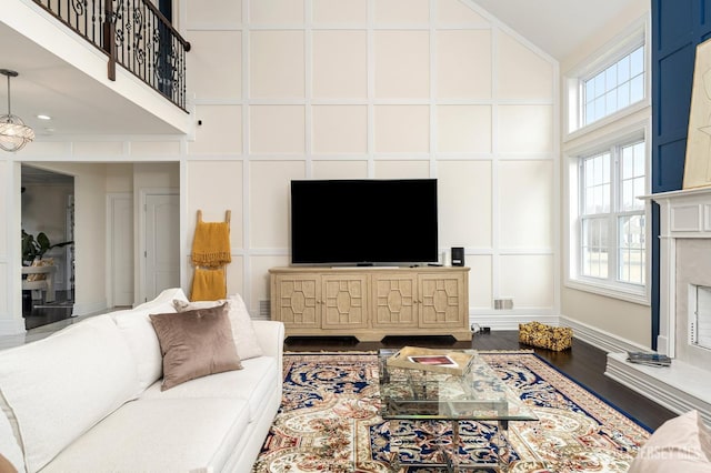 living room with a decorative wall, wood finished floors, a towering ceiling, and a premium fireplace