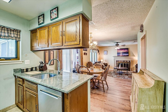 444 Dahlia Plz, Monroe, NJ 08831 - kitchen with stainless steel dishwasher, a sink, a glass covered fireplace, a ceiling fan, and light wood-style flooring