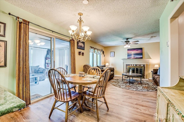 444 Dahlia Plz, Monroe, NJ 08831 - dining room featuring a chandelier, a textured ceiling, light wood finished floors, a glass covered fireplace, and a ceiling fan
