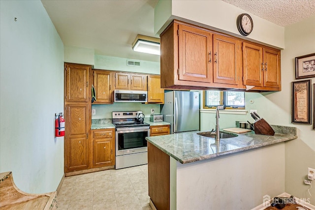 444 Dahlia Plz, Monroe, NJ 08831 - kitchen featuring appliances with stainless steel finishes, a sink, a peninsula, brown cabinetry, and light stone counters