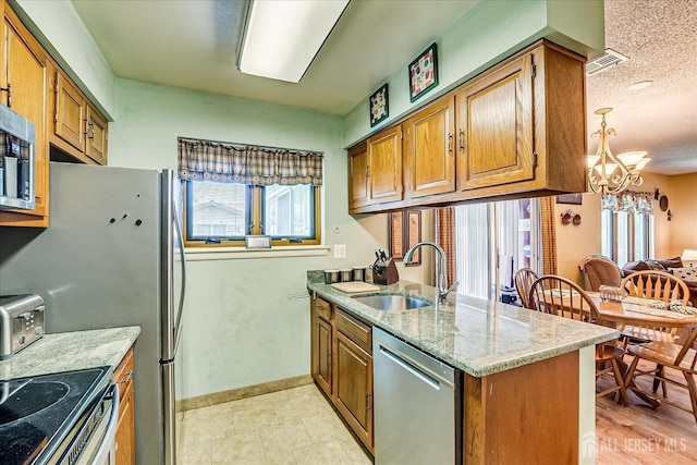 444 Dahlia Plz, Monroe, NJ 08831 - kitchen featuring appliances with stainless steel finishes, a sink, brown cabinets, a chandelier, and a textured ceiling