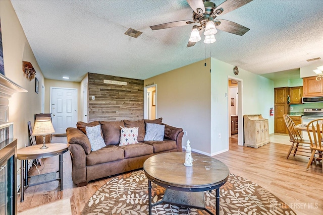 444 Dahlia Plz, Monroe, NJ 08831 - living room featuring ceiling fan, light wood finished floors, a textured ceiling, a fireplace, and baseboards