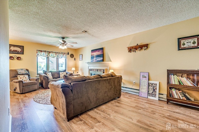 444 Dahlia Plz, Monroe, NJ 08831 - living area with light wood-style floors, ceiling fan, a textured ceiling, a baseboard radiator, and a glass covered fireplace