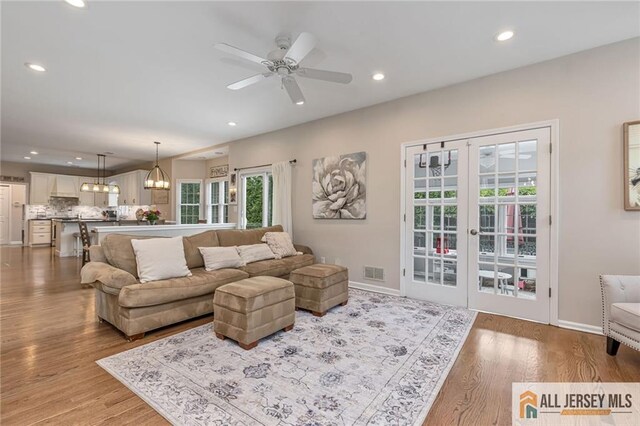 living room with light wood-type flooring, recessed lighting, ceiling fan, french doors, and baseboards