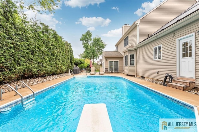 view of pool featuring entry steps, a diving board, and a patio