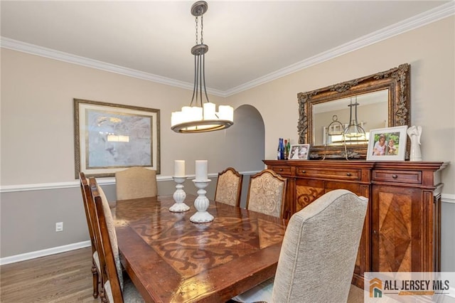 dining room with crown molding, wood finished floors, a chandelier, arched walkways, and baseboards