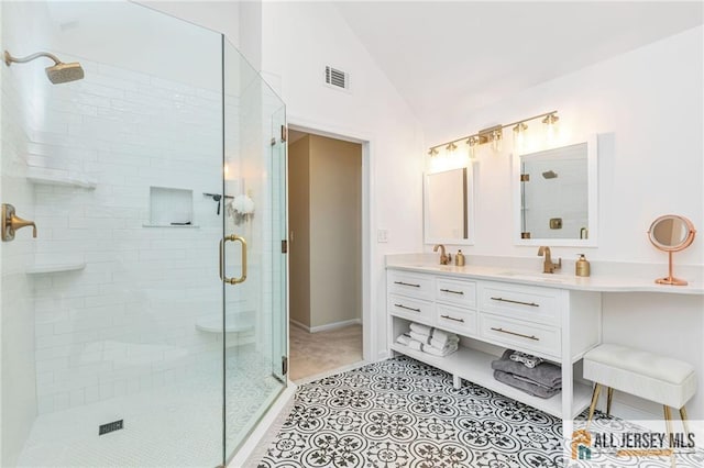 bathroom featuring vaulted ceiling, a stall shower, double vanity, baseboards, and tile patterned floors