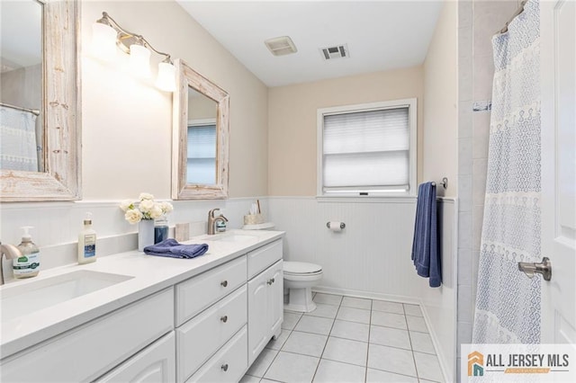 bathroom featuring toilet, tile patterned flooring, a wainscoted wall, double vanity, and a shower with curtain