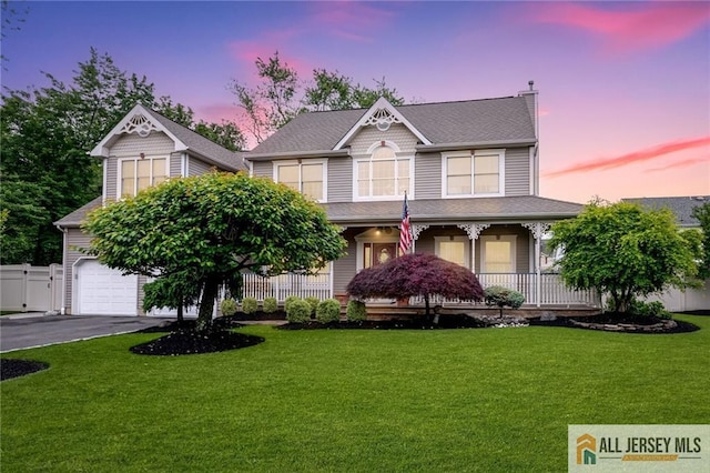 victorian home featuring covered porch, a garage, asphalt driveway, and a shingled roof