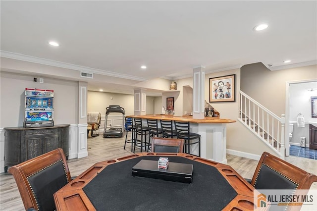 recreation room featuring ornamental molding, light wood-style flooring, recessed lighting, and a community bar