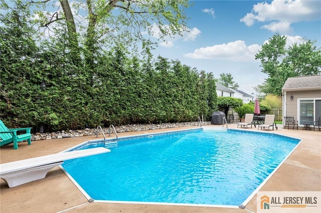 view of swimming pool featuring a diving board, fence, and a patio area