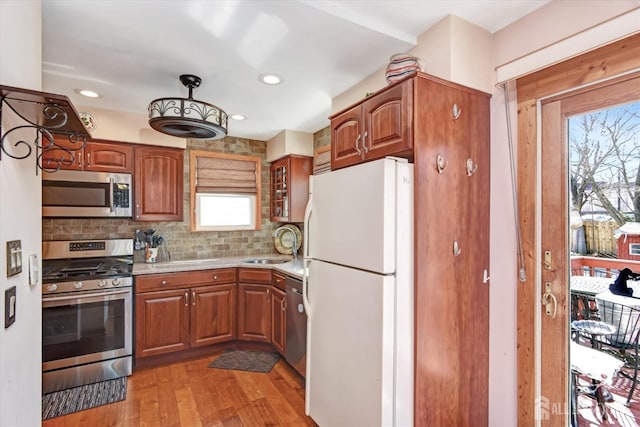 352 Parker Ave, South Amboy, NJ 08879 - kitchen featuring appliances with stainless steel finishes, backsplash, light wood finished floors, brown cabinetry, and recessed lighting