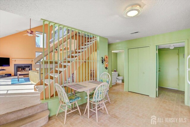 dining area with vaulted ceiling, a textured ceiling, and ceiling fan