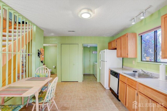 kitchen featuring sink, a textured ceiling, independent washer and dryer, and dishwasher