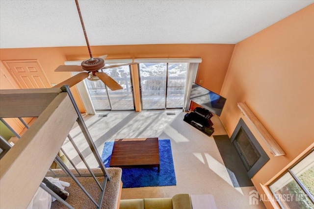 carpeted living room with ceiling fan and a textured ceiling