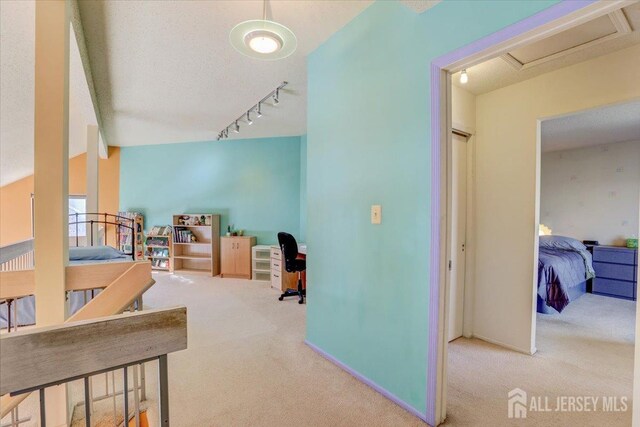 corridor with rail lighting, carpet, and a textured ceiling