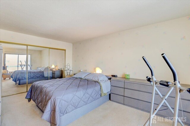 bedroom featuring light colored carpet, a closet, and a textured ceiling