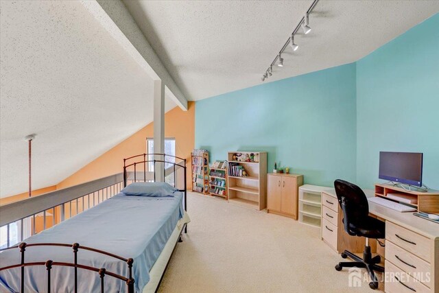 carpeted bedroom featuring lofted ceiling with beams, track lighting, and a textured ceiling