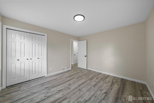 unfurnished bedroom with light hardwood / wood-style flooring and a closet