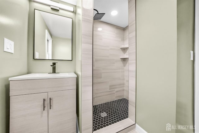 bathroom with tiled shower and vanity