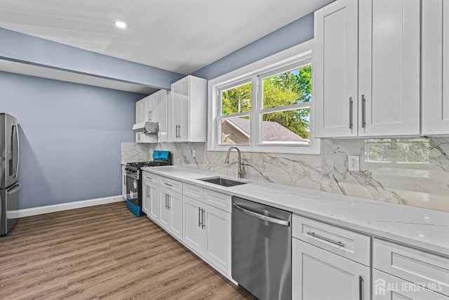 790 Ridge Rd, South Brunswick, NJ 08852 - kitchen with stainless steel appliances, under cabinet range hood, white cabinetry, light stone counters, and light wood finished floors