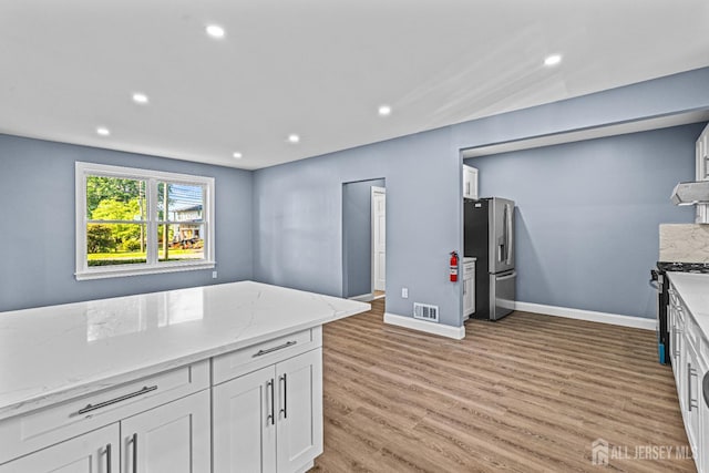 790 Ridge Rd, South Brunswick, NJ 08852 - kitchen with appliances with stainless steel finishes, range hood, white cabinets, light wood-style flooring, and light stone countertops