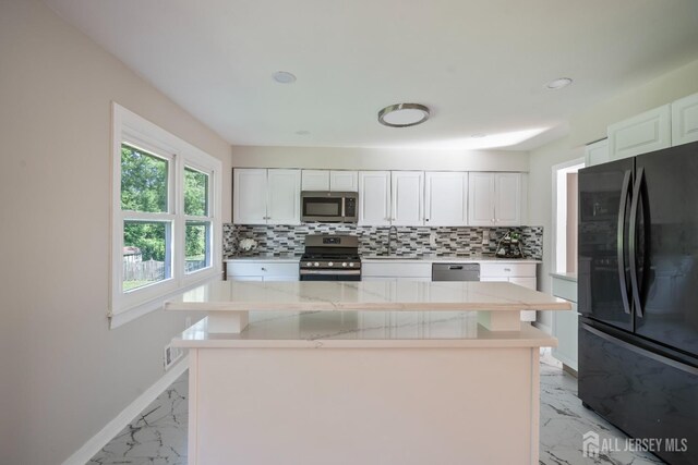 34 Hershey Rd, East Brunswick, NJ 08816 - kitchen featuring appliances with stainless steel finishes, light marble finish floors, decorative backsplash, white cabinetry, and baseboards