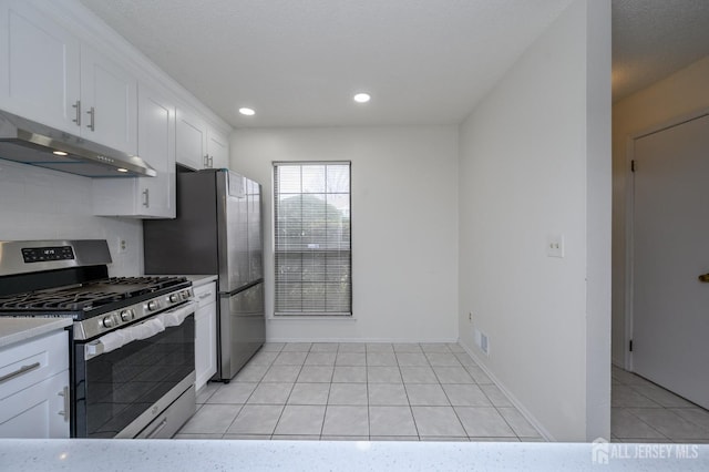 kitchen with light tile patterned floors, light countertops, white cabinets, stainless steel gas range, and under cabinet range hood