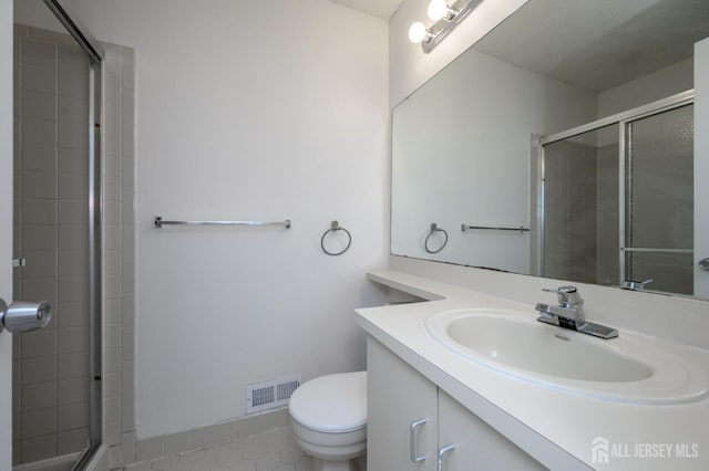 bathroom featuring toilet, visible vents, tiled shower, and vanity