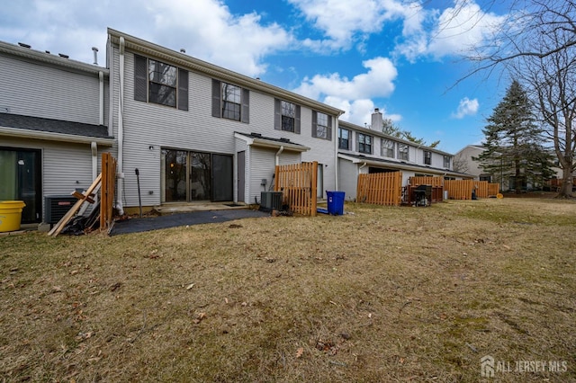 back of property with central AC and a lawn