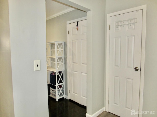 hallway featuring dark wood-style floors, baseboards, and crown molding