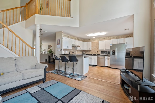 181 Windsong Cir E, Brunswick, NJ 08816 - living room with light wood-style floors, a high ceiling, and stairs