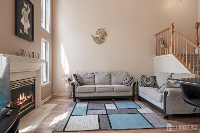 181 Windsong Cir E, Brunswick, NJ 08816 - living area featuring wood finished floors, a high ceiling, a fireplace, baseboards, and stairway