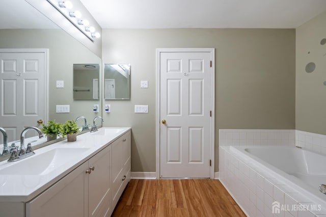 181 Windsong Cir E, Brunswick, NJ 08816 - full bathroom featuring wood finished floors, double vanity, a bath, and baseboards