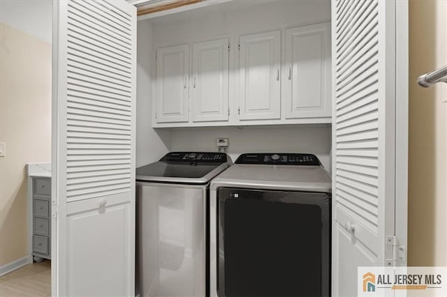 clothes washing area with baseboards, cabinet space, and washing machine and clothes dryer