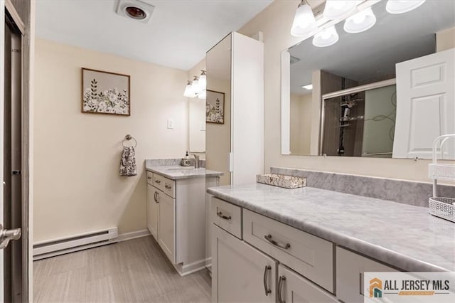 bathroom featuring a stall shower, a baseboard radiator, vanity, and baseboards